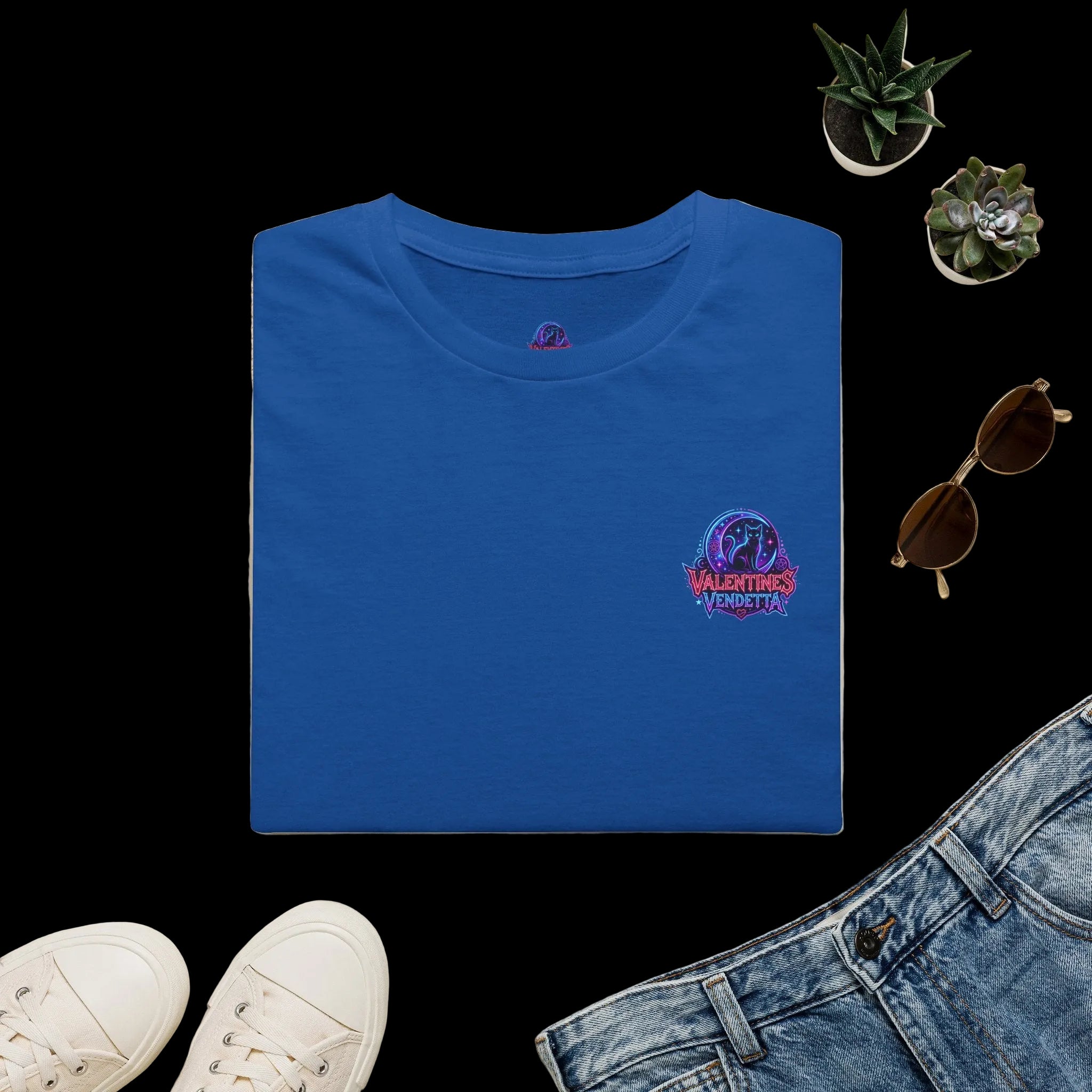 Blue t-shirt with colorful text on a light surface with accessories like a hat, sunglasses, and shoes.
